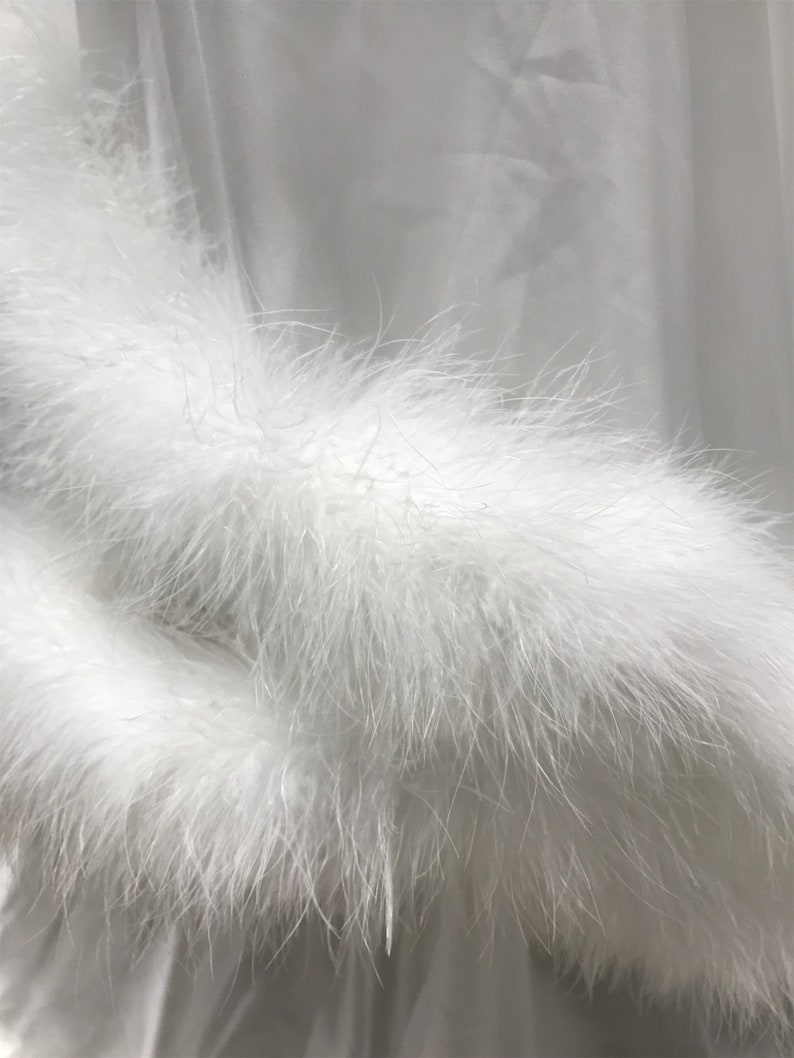May include: White satin robe with a fluffy white feather trim around the cuffs.
