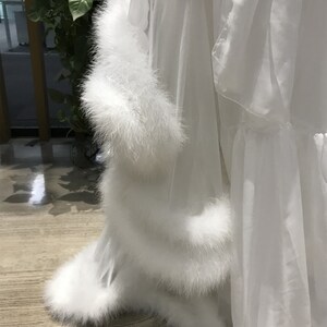May include: White sheer robe with a fluffy white fur trim around the bottom and sleeves.