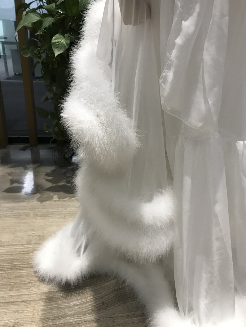 May include: White sheer robe with a fluffy white fur trim around the bottom and sleeves.