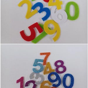 Puede incluir: Dos juegos de números de fieltro, un juego en colores sólidos y el otro juego con purpurina. Los números del primer juego son amarillo, verde, rojo, azul y blanco. Los números del segundo juego son naranja, dorado, plateado, azul, morado y rosa.