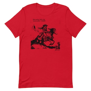 Könnte beinhalten: Rotes T-Shirt mit einer Schwarz-Weiß-Illustration einer Frau, die auf einem Pferd reitet. Der Text "the only hell my mama ever raised" ist auf dem T-Shirt aufgedruckt.