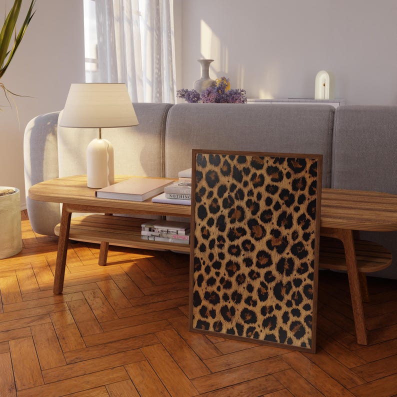May include: A framed print of a brown and black leopard print pattern. The print is hanging on a wall in a living room setting.
