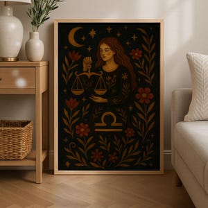 May include: A framed art print featuring a Libra zodiac illustration. The artwork depicts a woman holding scales, surrounded by floral and celestial elements in shades of gold, red, and brown against a dark background. The print is displayed in a room setting.