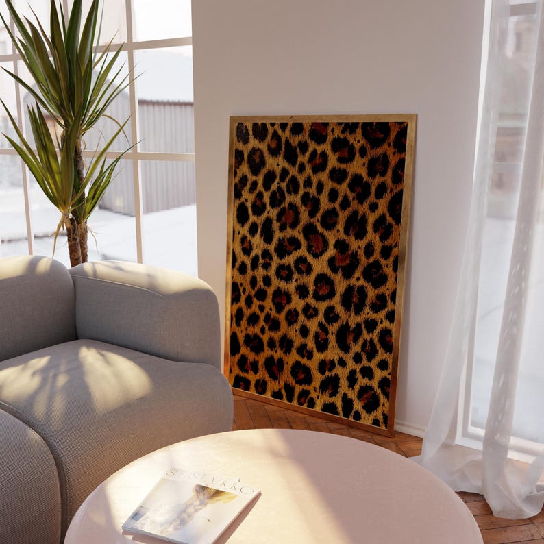May include: A framed print of a leopard print pattern in shades of brown, orange, and black. The print is hanging on a white wall in a living room setting.
