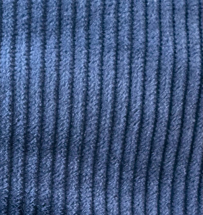 Op de afbeelding: Close-up van een blauwe corduroy stof met een verticale ribbelstructuur.