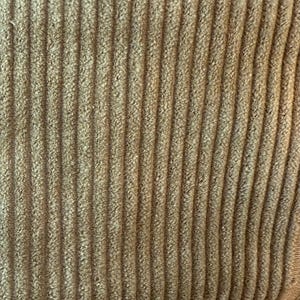 Op de afbeelding: Close-up van een bruine corduroy stof met een verticale ribbelstructuur.