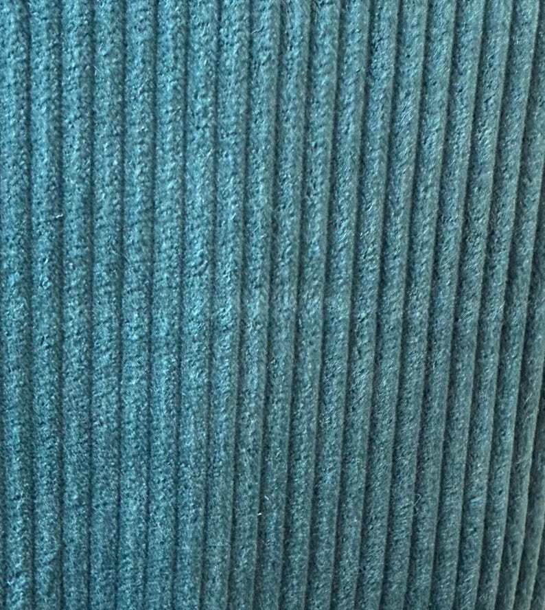 Op de afbeelding: Tealblauwe corduroy stof met verticale ribbels.