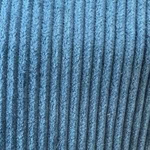 Op de afbeelding: Close-up van een blauwe corduroy stof met een textuur, geribbeld oppervlak.