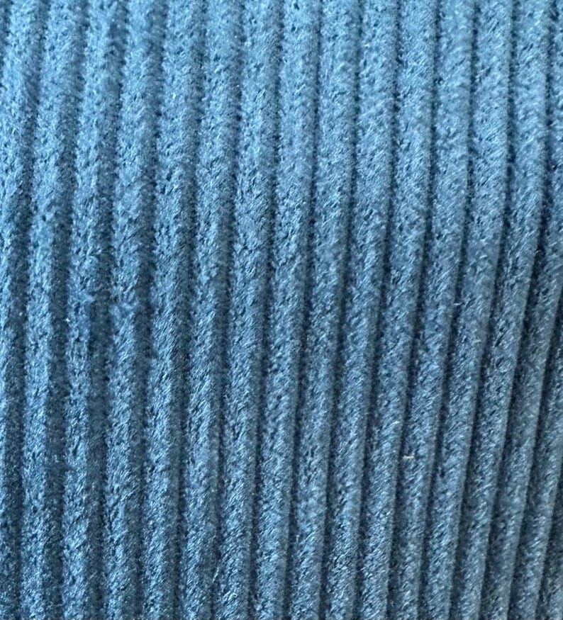 Op de afbeelding: Close-up van een blauwe corduroy stof met een textuur, geribbeld oppervlak.