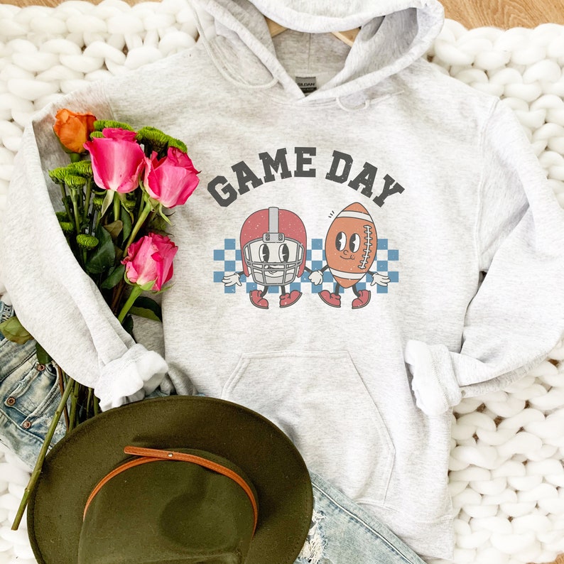 May include: A gray hoodie with a white graphic of a football helmet and football with the text "GAME DAY" in black.