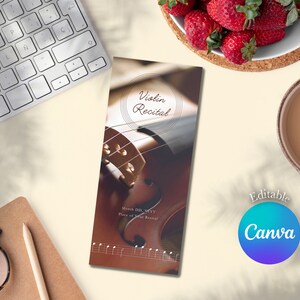 Puede incluir: Un violín marrón con un primer plano de las cuerdas y la palabra "Violin Recital" en un círculo en la parte superior de la página. El texto "Month DD, YYYY" y "Place of your Recital" están debajo del círculo. La página está sobre una superficie blanca con un teclado, una taza de café y un tazón de fresas.