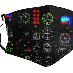 Könnte beinhalten: Schwarze Gesichtsmaske mit einem farbenfrohen Design eines Flugzeugcockpit-Instrumentenpanels. Das Design zeigt mehrere runde Anzeigen mit Zahlen und Zeigern sowie rechteckige Schalter und Anzeigen.
