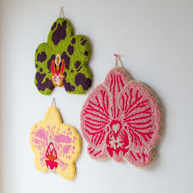 Pode incluir: Tr&ecirc;s pe&ccedil;as de parede feitas &agrave; m&atilde;o em forma de orqu&iacute;dea. A superior &eacute; verde com manchas roxas, a do meio &eacute; rosa com detalhes vermelhos e a inferior &eacute; amarela com detalhes rosa. Cada uma tem uma argola para pendurar.