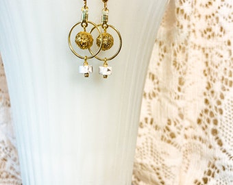 Petite gold hoops with lace textured gold bead dangling centers and white and grey dangling stone beads