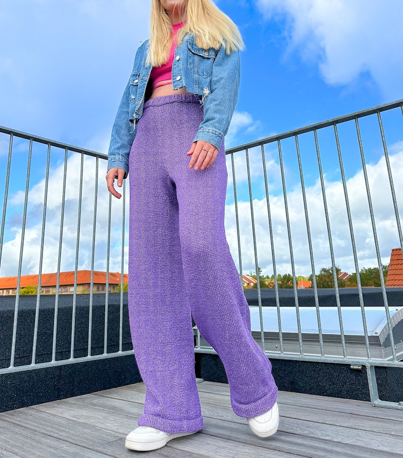 May include: Purple wide-leg knitted trousers with a high waist. The trousers are made from a soft, textured fabric and have a relaxed fit.