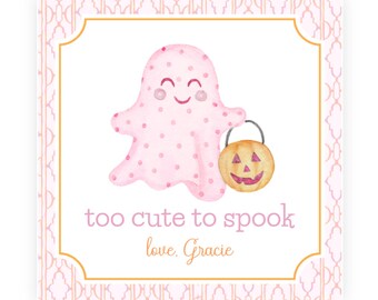 May include: A square card featuring a pink polka-dot ghost holding an orange jack-o'-lantern. The text reads "too cute to spook" and "love, Gracie" in orange script. The card has a white center with a gold border and a pink geometric pattern.