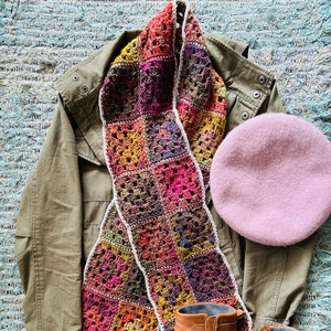 Puede incluir: Una chaqueta verde con una bufanda de ganchillo de colores, una boina rosa y botines de cuero marrón.