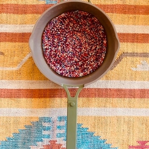 Peut inclure: Une poêle à frire de camping verte avec un dessous de plat en crochet à l'intérieur. Le dessous de plat est rouge, blanc et bleu.