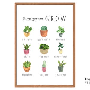 May include: A framed print with a white background features watercolour illustrations of potted plants, each labelled with a positive attribute like "self love" and "kindness." The words "things you can GROW" are at the top. The print is framed in a brown wooden frame.