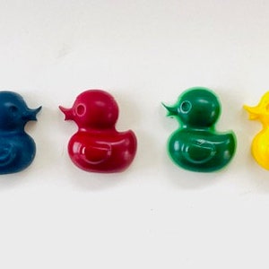 May include: Six rubber duck crayons in different colors: blue, dark blue, red, green, yellow, and orange. The crayons are shaped like rubber ducks.