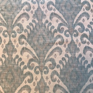 May include: A close-up of a fabric with a blue and white damask pattern. The fabric has a subtle sheen and a textured surface.