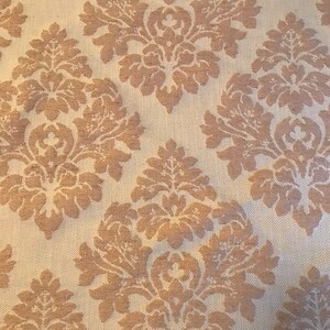 Puede incluir: Tela beige con un patrón de damasco marrón. El patrón presenta un diseño repetitivo de flores y hojas estilizadas.