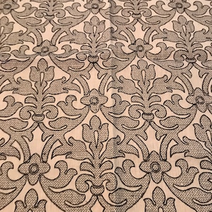 May include: A white fabric with a black damask pattern. The pattern features intricate floral designs and swirls.
