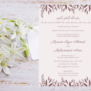 May include: A wedding invitation with floral accents and text in English and Arabic. The invitation is a soft beige color with burgundy-colored leaves and text. White flowers are in the foreground.