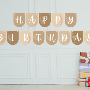 May include: A 'HAPPY BIRTHDAY' banner in white script on tan and brown pennants, each with a floral design. A stack of wrapped gifts in various colours with white ribbons is below the banner.