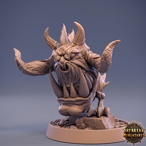 May include: A detailed miniature sculpture of a monstrous creature with horns, fangs, and a fierce expression. The creature is standing on a rocky base and is painted in a muted brown color.