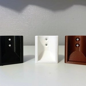 May include: Three wall mount brackets, one black, one white, and one brown.