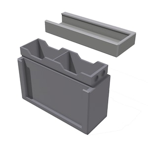 May include: A gray, modular storage container with a rectangular base and a separate, matching tray. The container has two internal compartments and two small holes on the top. The design is simple and modern.