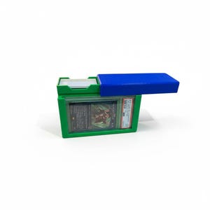 以下が含まれることがあります： 青い蓋が付いた緑色のプラスチック製カードホルダー。グレーディングされたトレーディングカードを収納。ホルダーには追加のカード用のコンパートメントがあります。内部のカードは、テキストとグラフィックデザインで表示されます。ホルダーは、トレーディングカードを保護し、保管するように設計されています。