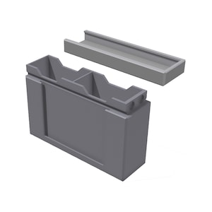 May include: A grey rectangular container with a separate lid. The container has internal dividers and a recessed area on the front. The lid is a long, narrow tray. The design is simple and functional.
