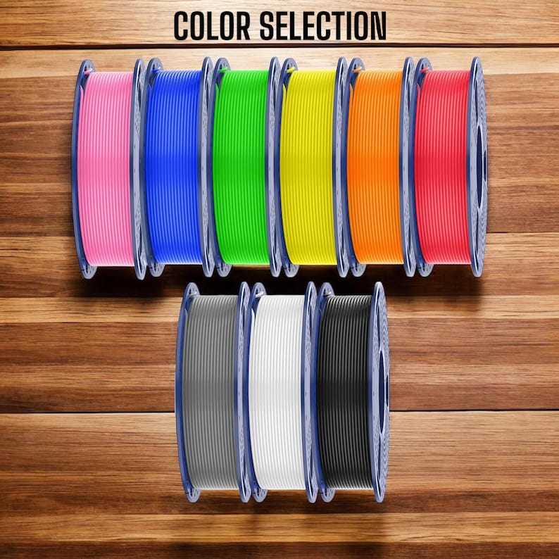 K&ouml;nnte beinhalten: Neun kreisf&ouml;rmige Spulen aus 3D-Drucker-Filament, angeordnet in zwei Reihen. Die obere Reihe zeigt Pink, Blau, Gr&uuml;n, Gelb, Orange und Rot. Die untere Reihe zeigt Grau, Wei&szlig; und Schwarz. Der Text COLOR SELECTION steht oben in der Mitte.
