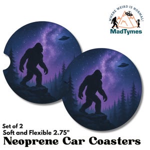 May include: Set of two 2.75 inch round neoprene car coasters featuring a silhouette of Bigfoot walking through a forest under a starry sky with a UFO in the distance. The text "Where Weird Is Normal!" is printed on the coasters.