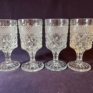 May include: Set of four clear glass stemmed drinking glasses with a diamond pattern.