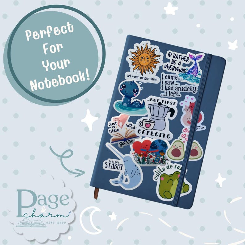 May include: A dark blue notebook covered in various colorful stickers, including a sun, a mermaid tail, a coffee pot with the text CAFECITO, a narwhal with the text FEELING STABBY, a green frog, two avocados, and a heart with flowers.