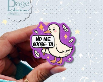 May include: A die-cut sticker featuring a white goose with an orange beak and feet, set against a purple background with yellow stars and white feathers. The goose holds a white sign with the black text NO ME GOOSE-TA.