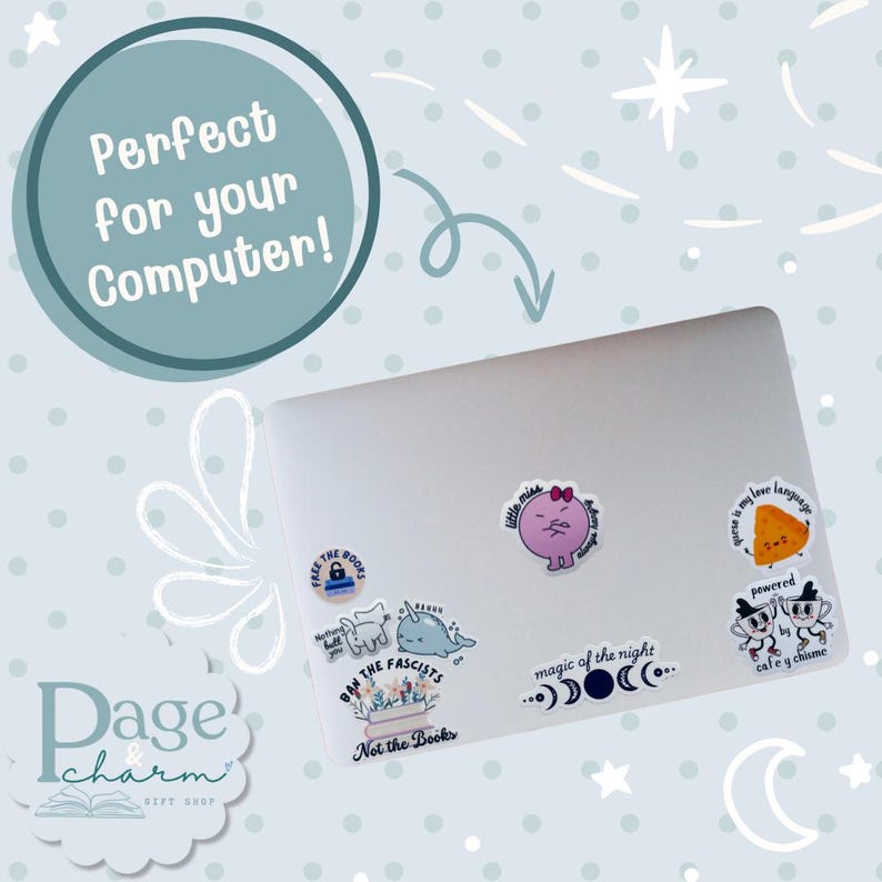 May include: A silver laptop decorated with various stickers including a narwhal, a pink character, a slice of cheese with the text "cheese is my love language," and text-based stickers reading "Free the books," "Ban the fascists, not the books," and "magic of the night."
