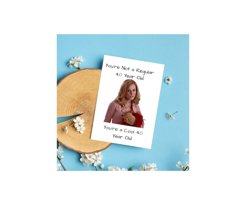 May include: A white card with the text "You're Not a Regular 40 Year Old. You're a Cool 40 Year Old." A woman with blonde hair is pictured on the card. She is wearing a pink shirt and holding a stuffed animal.