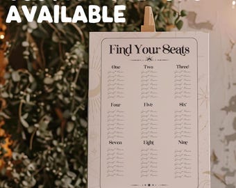 May include: A white seating chart with a celestial theme. The chart is titled "Find Your Seats" and lists the names of guests under each table number, from one to nine. The chart is decorated with stars, moons, and suns.