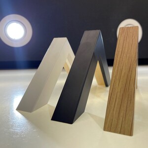 May include: Three picture frames in different colors and finishes: white, black, and wood grain.