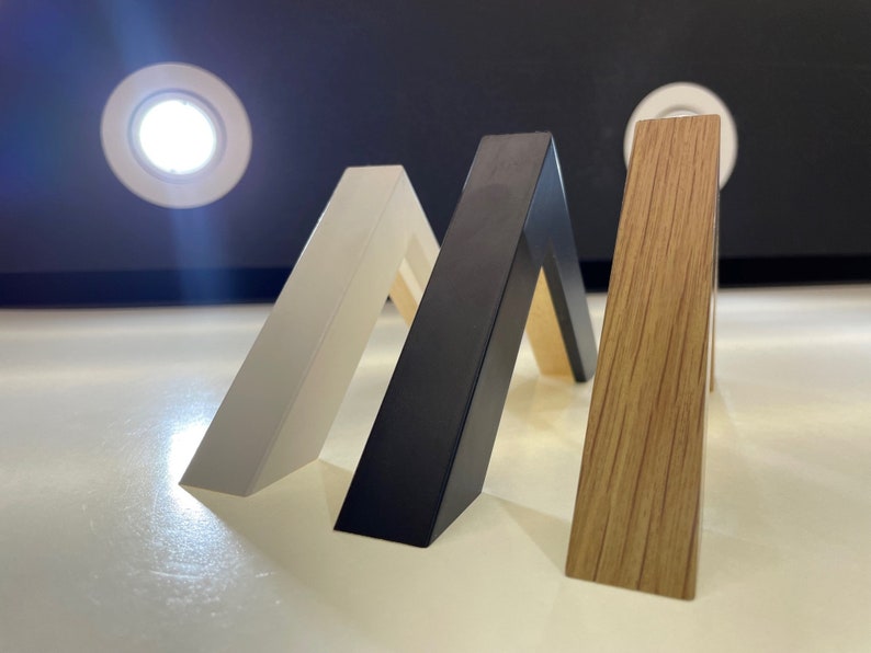 May include: Three picture frames in different colors and finishes: white, black, and wood grain.