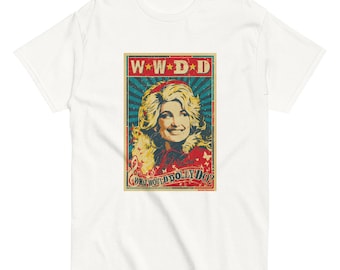May include: A white t-shirt featuring a rectangular graphic print of a blonde woman with a red headband. The design includes the text W*W*D*D and WHAT WOULD DOLLY DO? in a vintage-style poster aesthetic with red, blue, and yellow colour accents.
