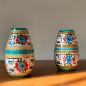May include: Two ceramic vases with a geometric pattern and floral designs in shades of blue, green, red, and white.