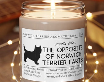 Może przedstawiać: Brązowa świeca sojowa z białą etykietą, na której widnieje napis "Aromaterapia Norwich Terrier" i "pachnie jak... Przeciwieństwo Norwich Terrier Farts". Etykieta zawiera również sylwetkę Norwich Terriera i tekst "Całkowicie naturalna mieszanka sojowa, 50-40 godzin palenia, nietoksyczna, bez barwników".