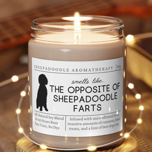 May include: A brown candle with a white label that reads "SHEEPADOODLE AROMATHERAPY" and "smells like... THE OPPOSITE OF SHEEPADOODLE FARTS". The label also includes the text "All Natural Soy Blend", "50-60 Hours Burn", "Non-Toxic, No Dye", and "Infused with unconditional love, massive amounts of cuteness, extra treats, and a hint of best dog ever."