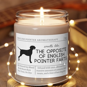 May include: A brown soy candle with a white label that reads "English Pointer Aromatherapy" and "smells like The Opposite of English Pointer Farts". The label also includes a silhouette of an English Pointer dog and the text "All Natural Soy Blend, 50-40 Hours Burn, Non-Toxic, No Dye". The candle is sitting on a wooden coaster.