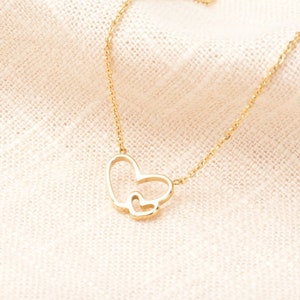May include: A gold necklace with a double heart pendant. The larger heart is open and the smaller heart is inside it.